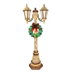 a lighted christmas wreath on top of a lamp post with two lights attached to it