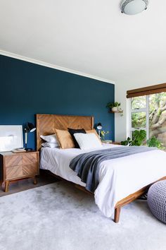 a bed sitting in a bedroom next to a window with blue walls and white carpet