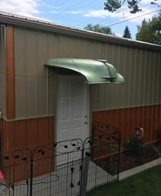 a garage with a green awning over the door and black iron fence around it