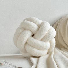 a white ball of yarn sitting on top of a bed