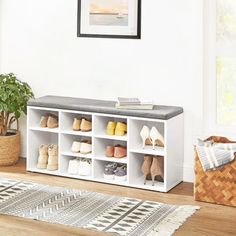 a white shoe rack with shoes on it in a living room next to a potted plant