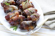 bacon wrapped dates on a white plate