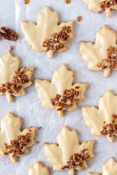 maple leaf shaped cookies with white frosting and pecans on parchment paper, ready to be eaten