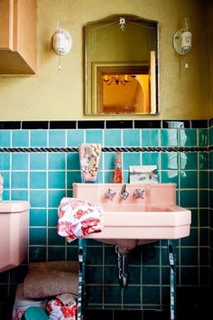 a pink sink sitting next to a toilet in a bathroom with blue tiles on the walls