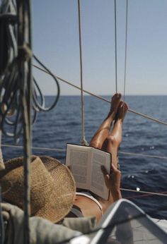 a person reading a book while sitting on a boat