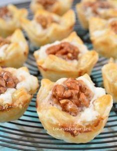 several small pastries on a wire rack with nuts in the center and cream cheese filling