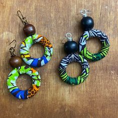 These multi-colored fabric hoop earrings are adorned with a coordinating wood bead. Fabric colors:  *Green/Black/White with Black bead *Blue/Brown/Orange with Brown bead *This item is handmade.  Due to variations in the fabric print, each item may look slightly different from the other. Wood Beaded Earrings, Fabric Hoop Earrings, Lady Accessories, Africa Earrings, Waist Jewelry, Beading Crafts, Earrings Wood, African Earrings, Earrings Hoops