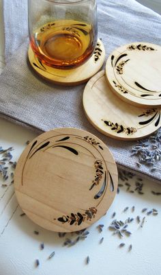 four wooden coasters sitting on top of a table next to a glass filled with liquid