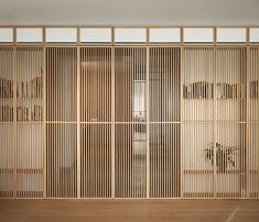 an empty room with wooden slats on the wall and bookshelves behind it