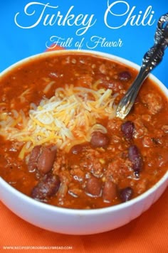 a bowl of turkey chili with beans and cheese on the side, ready to be eaten