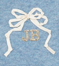 a blue sweater with a bow and the word j b on it's side