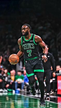 a basketball player dribbling the ball down the court in front of an audience