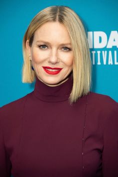 a woman with blonde hair wearing a burgundy dress and red lipstick is smiling at the camera