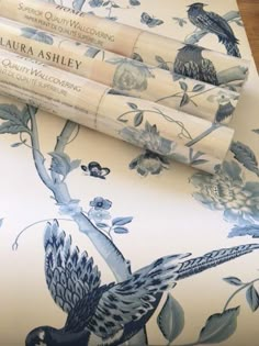 three rolls of blue and white wallpaper with birds on them, sitting next to each other