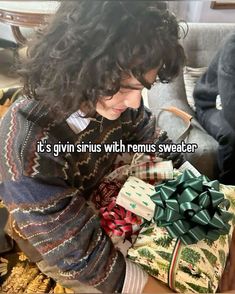 a woman sitting on top of a couch next to wrapped presents and the caption it's given sinus with remus sweater