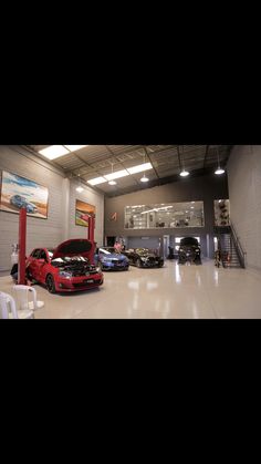 two cars parked in a garage with their hoods open