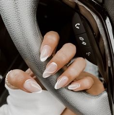 a woman's hand holding onto the steering wheel of a car with white nails