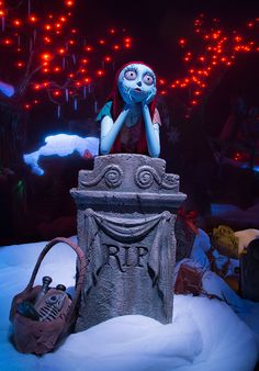 a creepy doll sitting on top of a cement block in front of red and blue lights