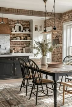 a kitchen with brick walls and wooden table surrounded by chairs, potted plant on the counter