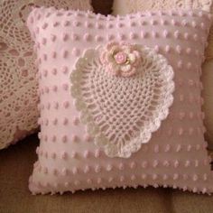 a pink pillow with a crocheted heart on it