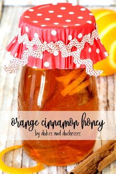 orange cinnamon honey in a mason jar with an orange ribbon around the top and some cinnamon sticks next to it