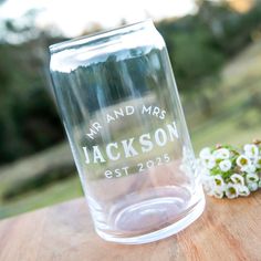 a clear glass vase sitting on top of a wooden table next to small white flowers