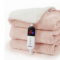 a digital thermometer sitting on top of four folded pink and white towels in front of each other