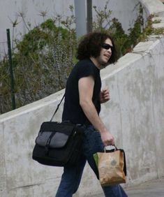 a man walking down the street with a black bag