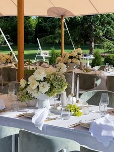 an outdoor dining area with tables, chairs and flowers in vases on the table