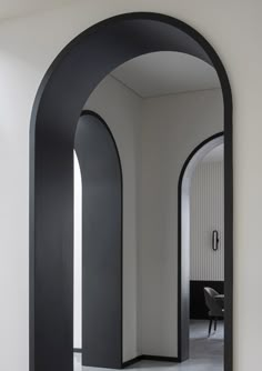 an arch shaped mirror in the middle of a room with white walls and flooring