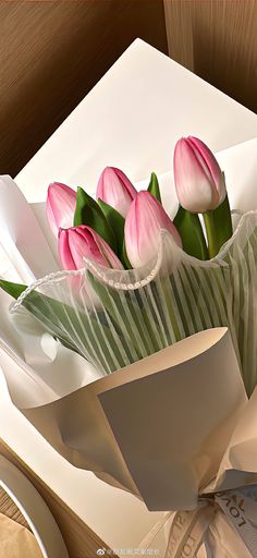 a bouquet of pink tulips in a paper bag