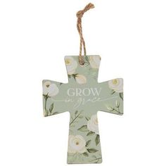 a cross shaped ornament with white flowers and the words grow in grace on it