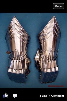 two metal armors are shown on a blue surface with gold rivets and studded straps