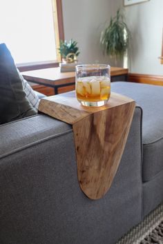 a glass with ice sitting on top of a wooden table next to a gray couch