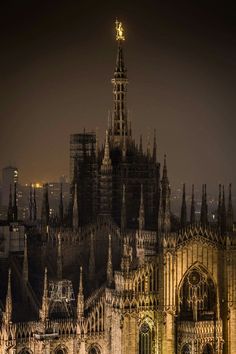 an old cathedral lit up at night with scaffolding on it's sides