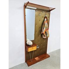 a coat rack with a mirror and some clothes hanging on the wall next to it