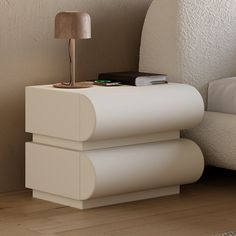 a white table with a lamp on top of it next to a bed and pillows