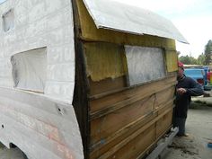 a man is standing next to a boat that has been built into the ground with wood planks