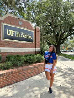 a woman standing in front of the university of florida sign