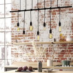 an industrial style light fixture hanging from a brick wall above a table with plates and utensils on it