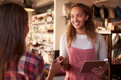 a woman in an apron is talking to another woman who is holding a clipboard