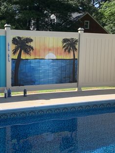 a painting on the side of a fence next to a swimming pool with blue water