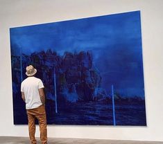 a man standing in front of a blue painting