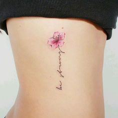 a woman's lower back with a pink flower on her left side ribcage