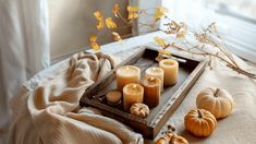 a tray with candles and pumpkins sitting on a bed