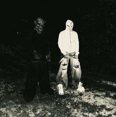 two people standing next to each other in the dark with one person wearing a mask