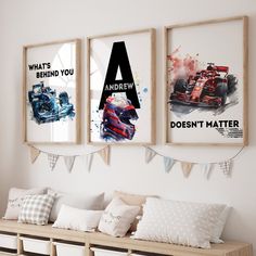 three framed racing posters hang on the wall above a bench with storage bins underneath