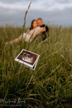 a couple kissing in tall grass with an old photo on the ground next to them