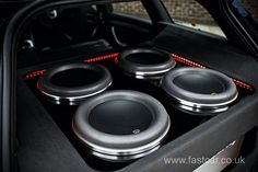 four speakers in the back of a car with its door open and red lights on