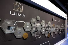 an exhibit wall with various hexagonal objects on it's sides and the words lumix written in gold